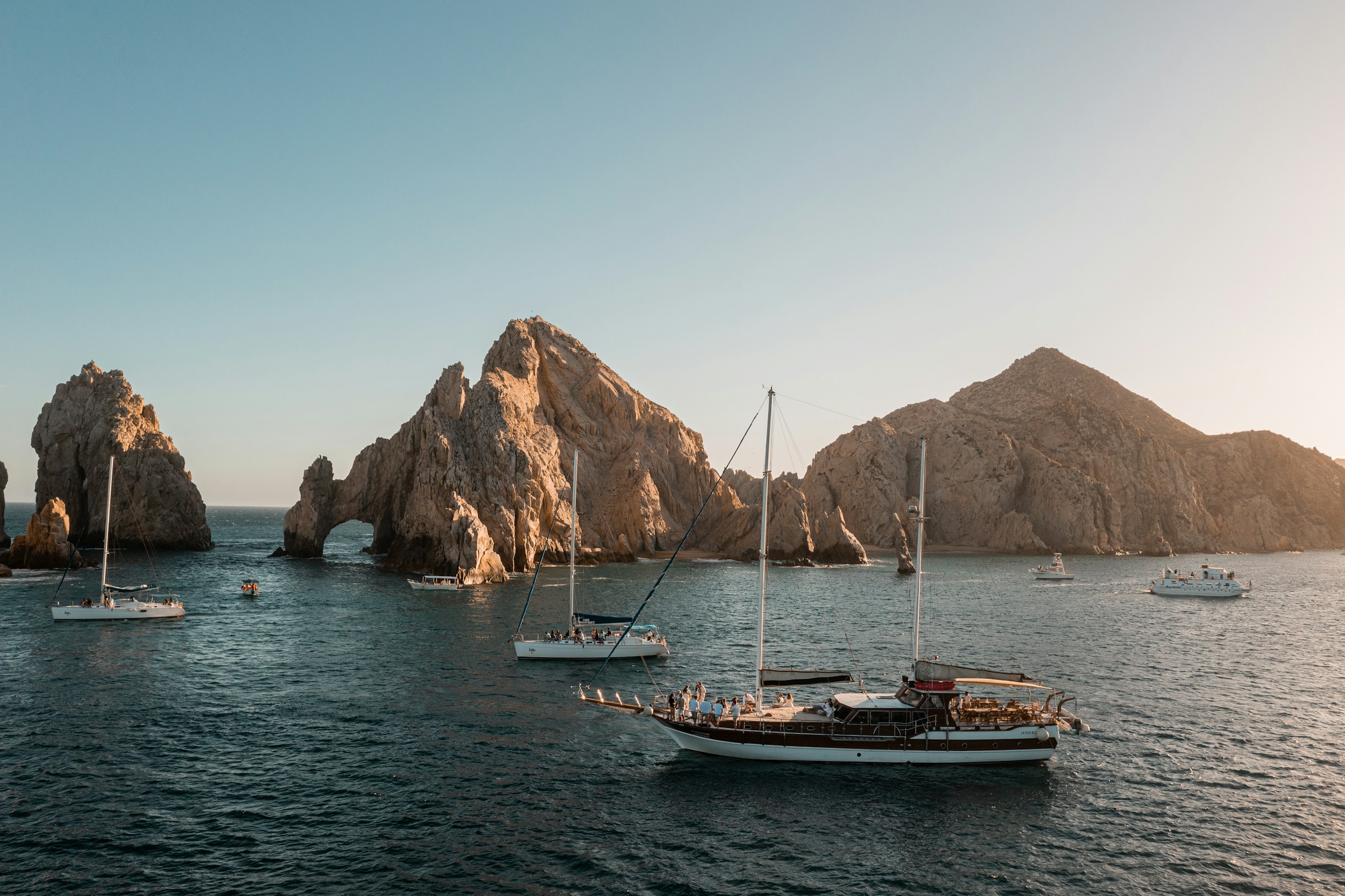 Sailboats anchored by the Arch at golden hour — Cabo San Lucas
